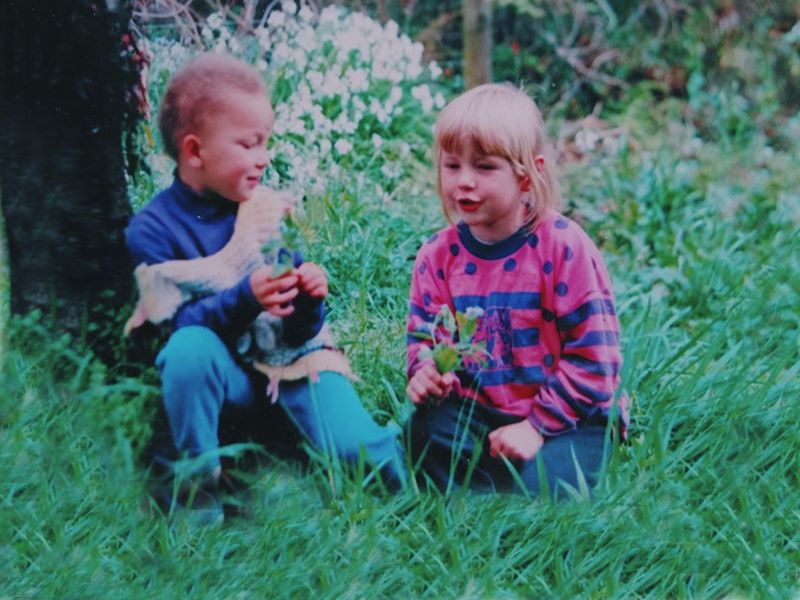 6 year old girl with alopecia next to 'normal' 6 year old girl, sitting in grassy field.