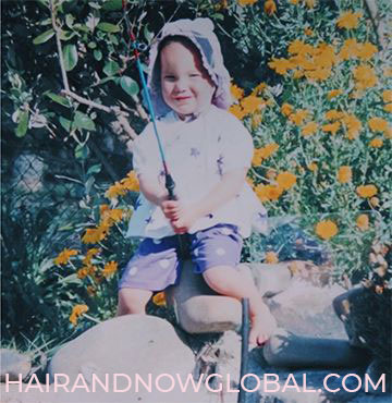 Small girl age three with alopecia fishing in garden pond