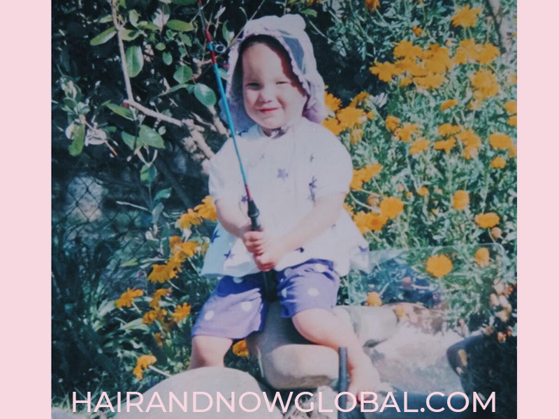 Small girl age three with alopecia fishing in garden pond